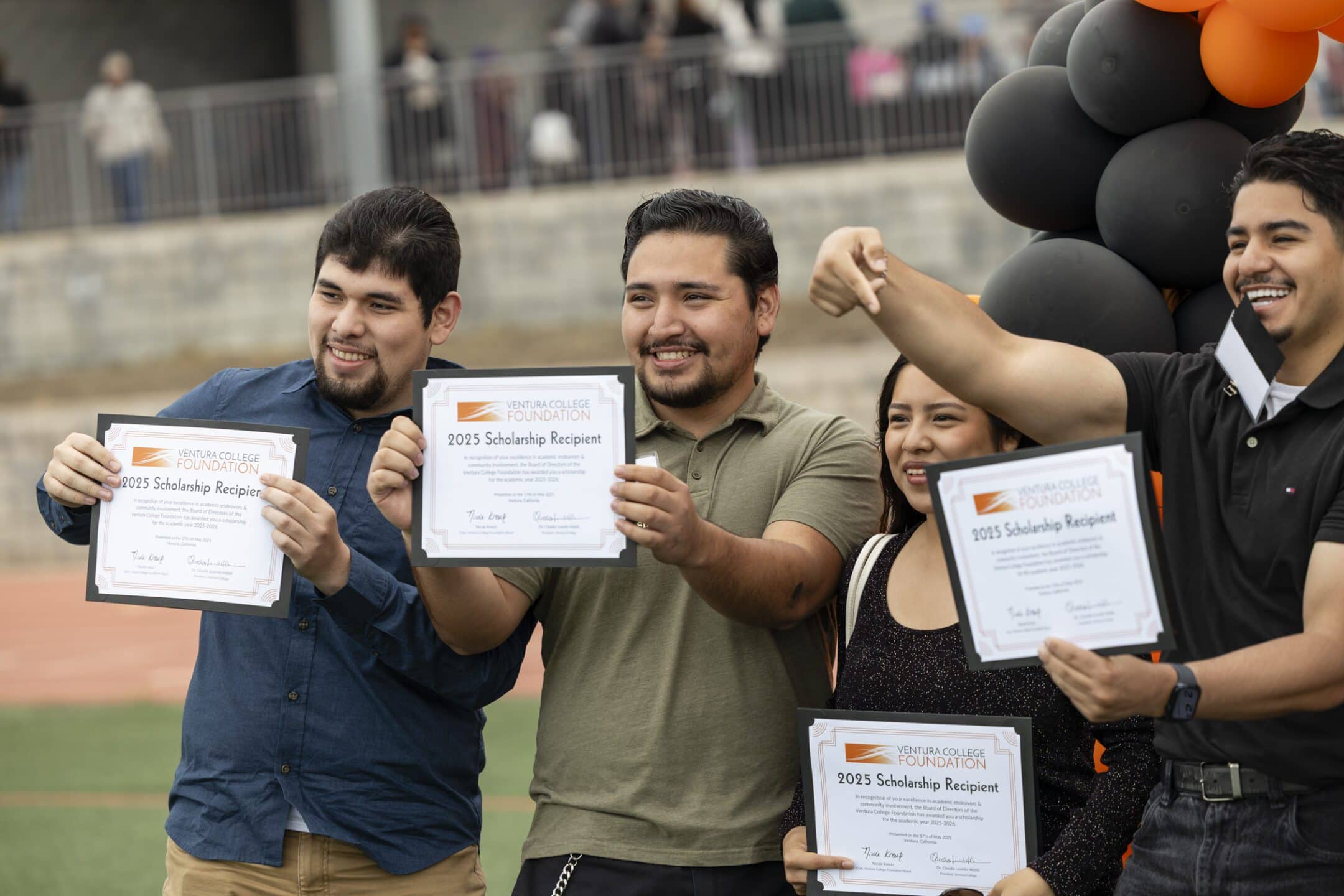 graduates holding up certificates
