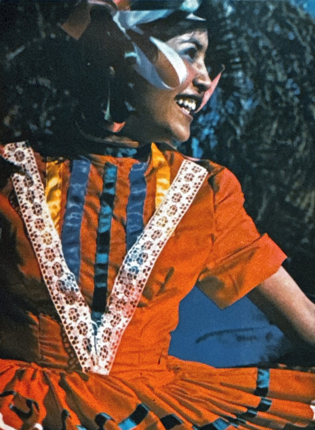 Female astronaut in orange suit smiling outdoors, celebrating alumni success.