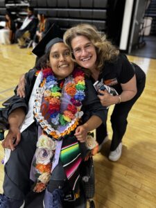 Happy graduate in cap and gown with a woman at Ventura College graduation ceremony.