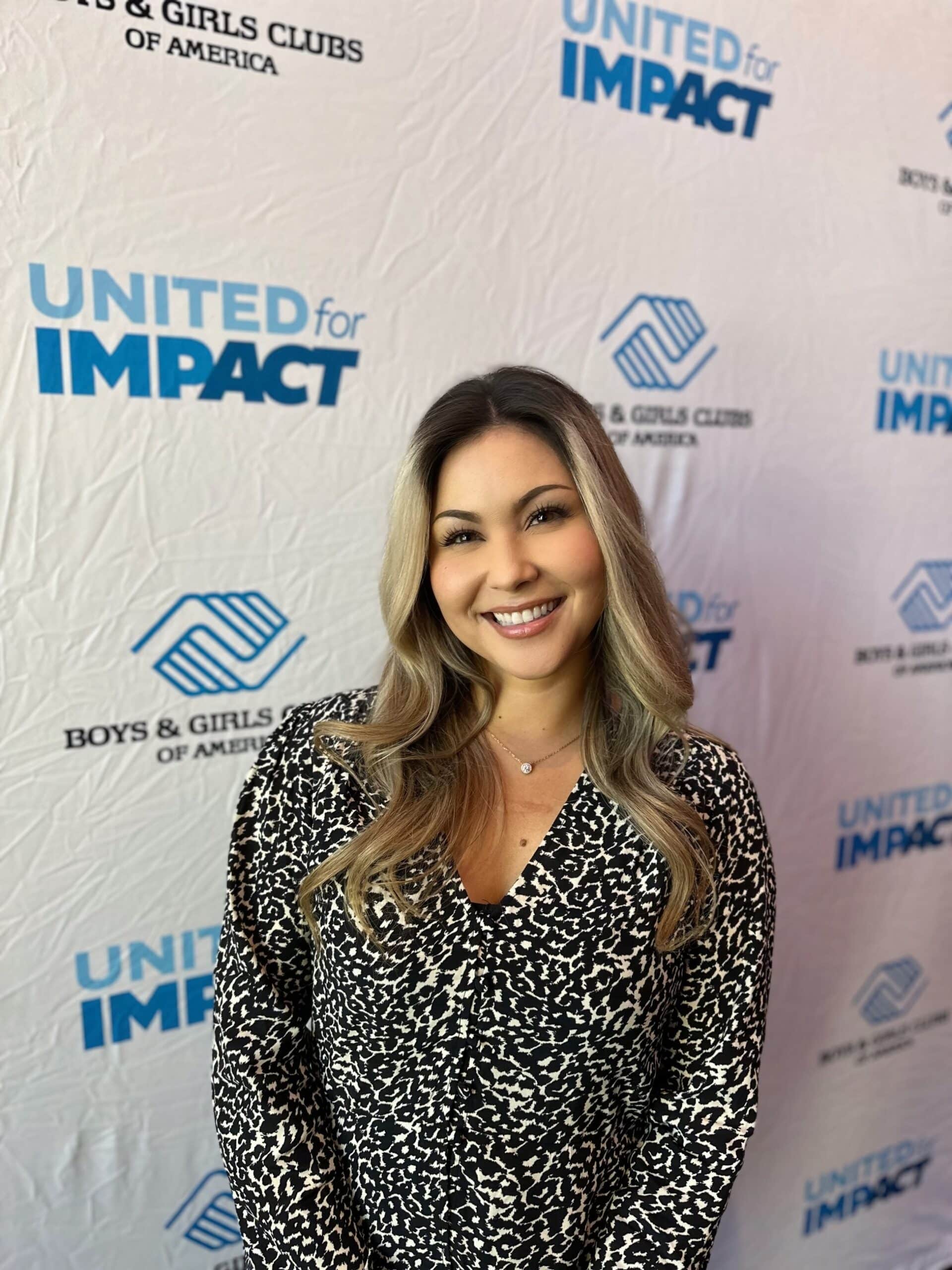 Smiling woman at United for Impact event with Ventura College Foundation backdrop.