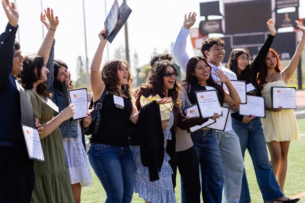 Students celebrating and holding certificates at Ventura College Foundation event.